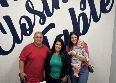 Realtor Elizabeth holding her baby alongside husband and wife clients at a home closing