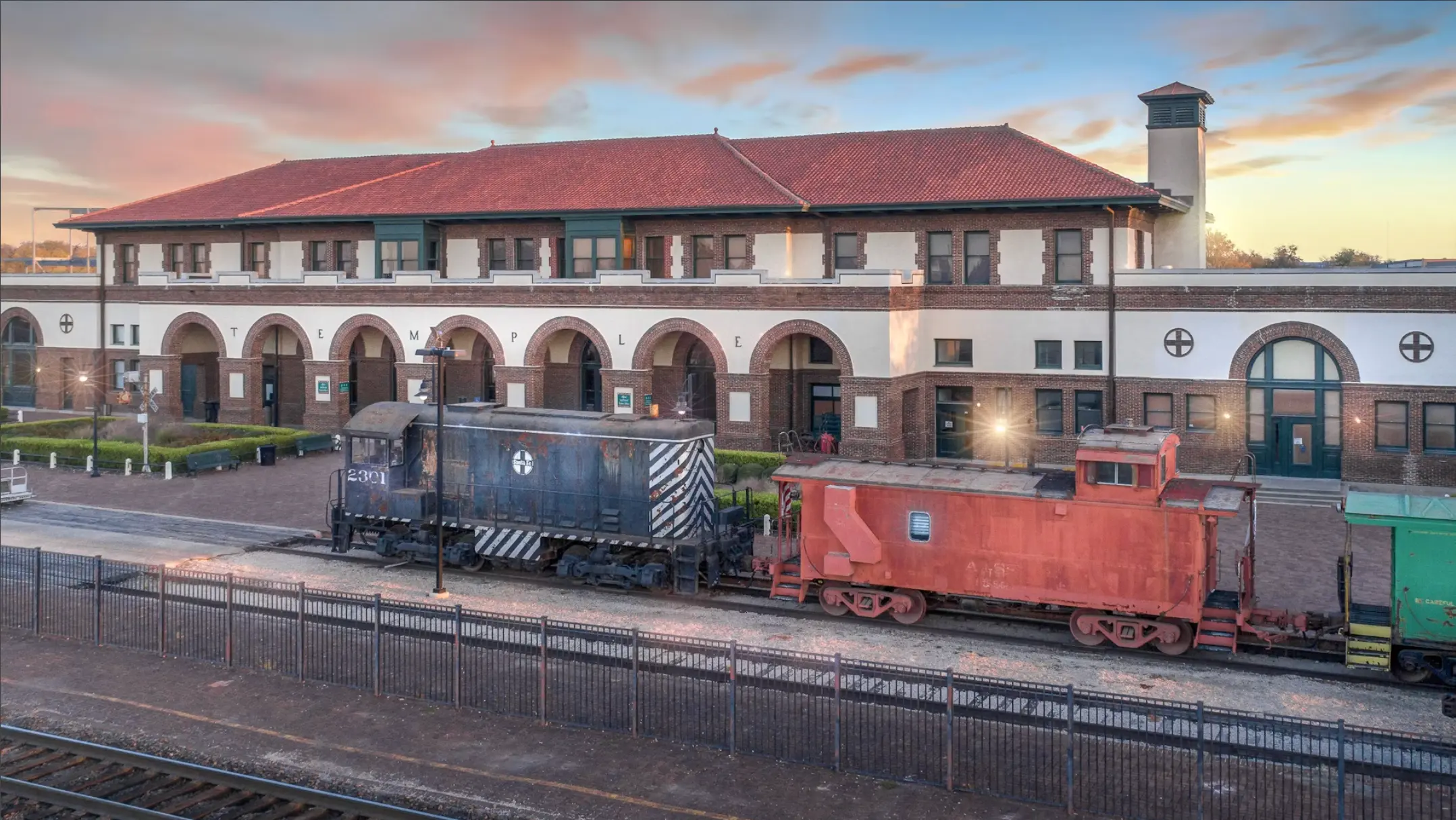 Historic Temple Railroad and Heritage Museum building with vintage train cars in front during sunset in Temple, TX